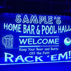 Puede incluir: Un letrero LED azul con el texto "SAMPLE'S HOME BAR & POOL HALL WELCOME" y un gráfico de jarra de cerveza y bola 8. El letrero también incluye la frase "Keep Your Beer and Butts Off the Felt! RACK 'EM!"