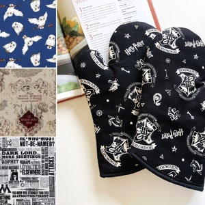 May include: A pair of black oven mitts with a white pattern featuring the Hogwarts crest, stars, and the words "Hogwarts" and "Harry Potter".