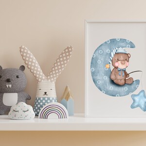 Puede incluir: Una impresi&oacute;n en acuarela enmarcada de un oso de peluche con gorro de dormir, sentado en una luna creciente azul con una estrella. La imagen est&aacute; rodeada de juguetes de peluche, incluyendo un oso gris, un conejito, una nube y un arco&iacute;ris.