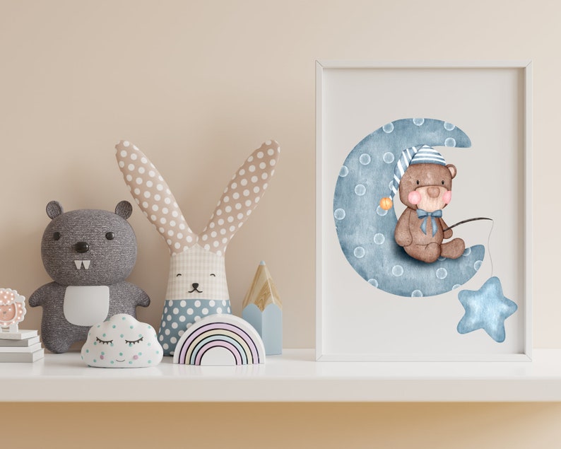 Puede incluir: Una impresi&oacute;n en acuarela enmarcada de un oso de peluche con gorro de dormir, sentado en una luna creciente azul con una estrella. La imagen est&aacute; rodeada de juguetes de peluche, incluyendo un oso gris, un conejito, una nube y un arco&iacute;ris.