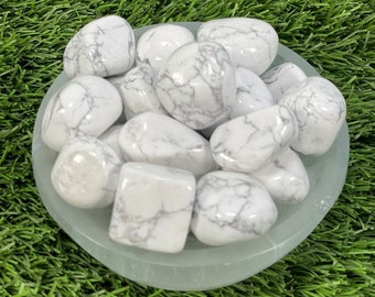 Puede incluir: Un cuenco de piedras de howlite blancas pulidas. Las piedras son lisas y tienen un patrón de mármol blanco y gris.