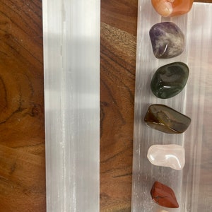 May include: A selenite charging plate with a variety of tumbled stones, including carnelian, amethyst, green aventurine, tiger's eye, rose quartz, red jasper, and a pink and white agate.