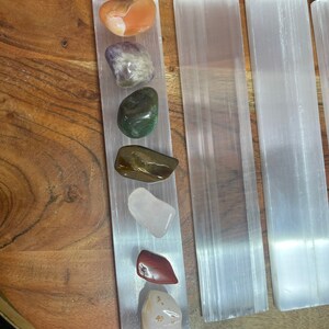 May include: A set of seven tumbled stones, including carnelian, amethyst, green aventurine, tiger's eye, rose quartz, red jasper, and citrine, arranged on a selenite charging plate.