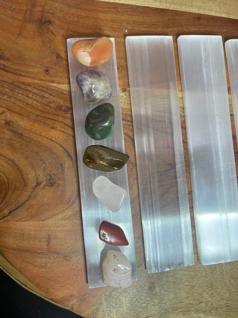May include: A set of seven tumbled stones, including carnelian, amethyst, green aventurine, tiger's eye, rose quartz, red jasper, and citrine, arranged on a selenite charging plate.