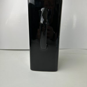 May include: A black ceramic mug with a large handle. The mug is tall and rectangular in shape.