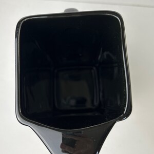 May include: A black ceramic jug with a wide mouth and a spout. The jug is empty and has a glossy finish.