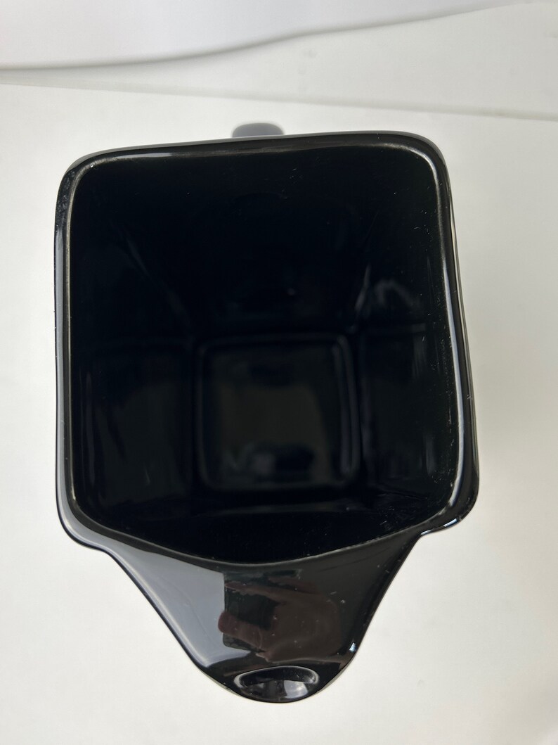 May include: A black ceramic jug with a wide mouth and a spout. The jug is empty and has a glossy finish.