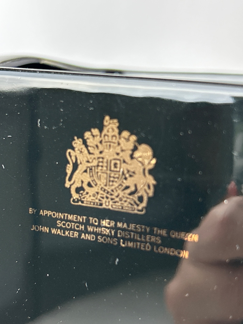 May include: A black box with a gold royal crest and the text "By Appointment to Her Majesty The Queen Scotch Whisky Distillers John Walker and Sons Limited London."
