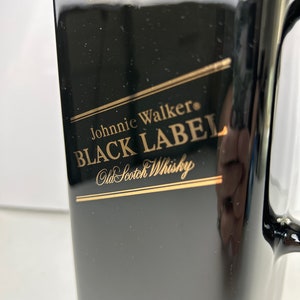 May include: Black bottle with a gold label that reads "Johnnie Walker&reg; BLACK LABEL Old Scotch Whisky".