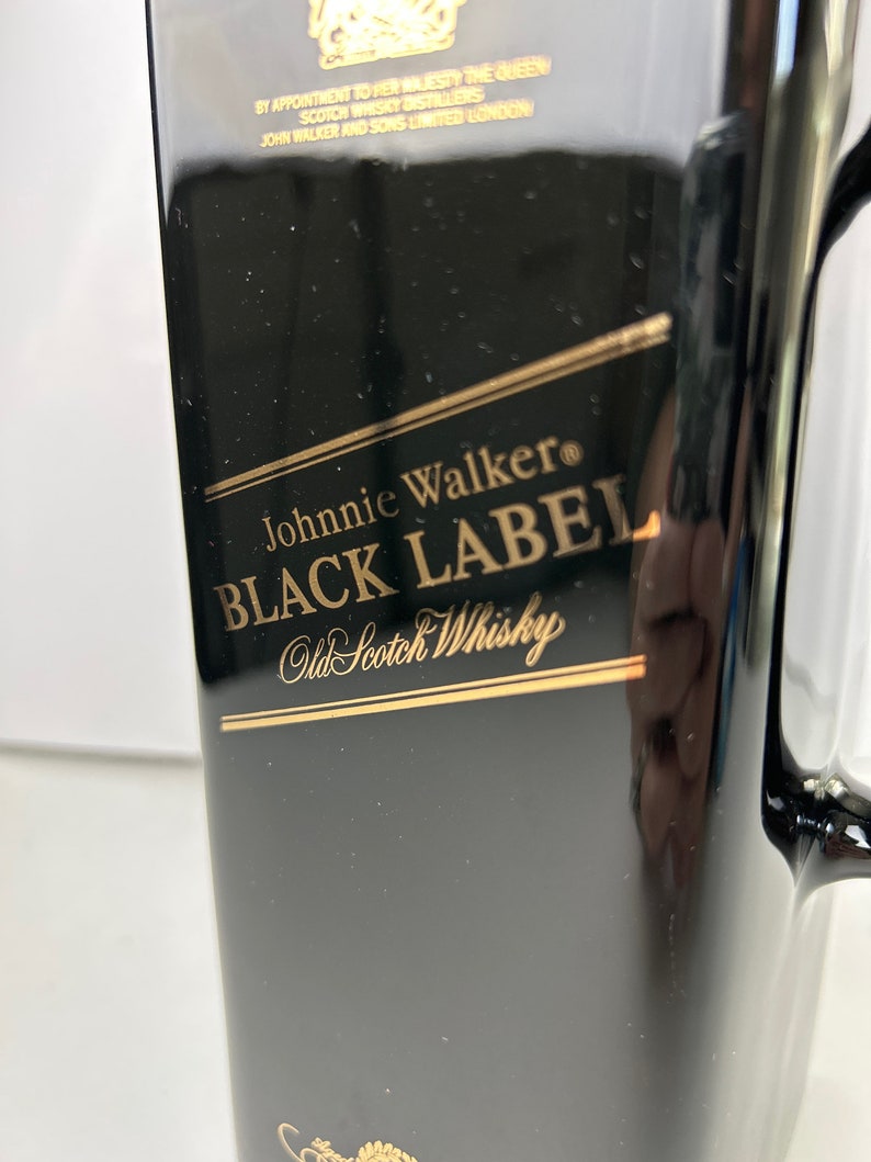 May include: Black bottle with a gold label that reads "Johnnie Walker&reg; BLACK LABEL Old Scotch Whisky".