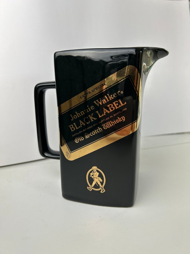 K&ouml;nnte beinhalten: Schwarzer Keramik-Krug mit goldenem Johnnie Walker Black Label Logo und einer Grafik eines laufenden Mannes. Das Etikett lautet "Extra Special", "Johnnie Walker", "Black Label", "Distilled, Blended and Bottled in Scotland", und "Old Scotch Whisky".