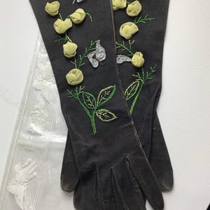 May include: A pair of black long gloves with embroidered yellow roses and butterflies. The gloves are in a clear plastic bag.