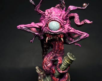 May include: A pink and purple painted miniature of a monstrous creature with a single large eye, multiple tentacles, and a gaping maw. The creature is standing on a base with a textured surface.