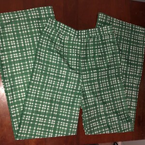 May include: Green and white checkered wide-leg pants. The pants have a high waist and a relaxed fit.