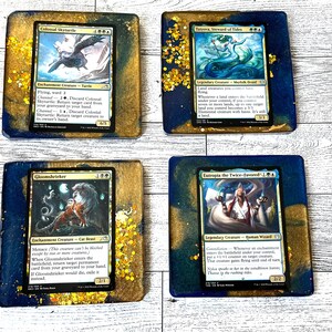 May include: Four Magic: The Gathering cards are displayed on coasters. The cards are "Colossal Skyturtle", "Tatyova, Steward of Tides", "Gloomshrieker", and "Eutropia the Twice-Favored". The coasters are blue with gold glitter.