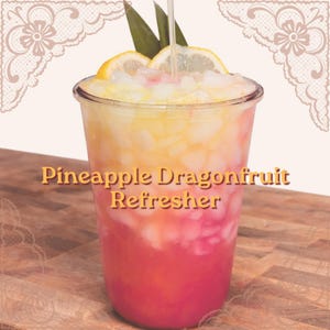 Pode incluir: Uma bebida refrescante Pineapple Dragonfruit Refresher em um copo de plástico transparente. A bebida tem camadas de rosa, amarelo e branco, coberta com gelo, rodelas de limão e uma folha verde. O texto "Pineapple Dragonfruit Refresher" é exibido.