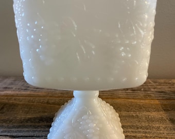 May include: White milk glass pedestal bowl with a grapevine design. The bowl is square and has a raised base.