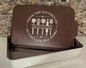May include: Brown baking dish with a removable lid. The lid has a white graphic that says "From the Kitchen of The Waldner's From the Kitchen of" with a star and kitchen utensil icons.
