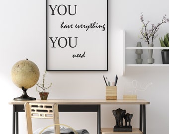 May include: Black framed print with the text "YOU have everything YOU need" on a white background. The print is hanging on a white wall above a wooden desk with a chair, a globe, and a plant.