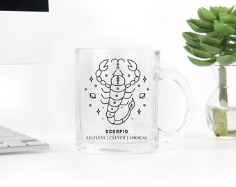 May include: A clear glass mug with a black line drawing of a scorpion and the text "SCORPIO SELFLESS | CLEVER | LOGICAL".