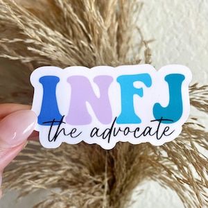 May include: A white sticker with the letters "INFJ" in blue, purple, and teal. The letters are in a retro font. Below the letters is the text "the advocate" in black.