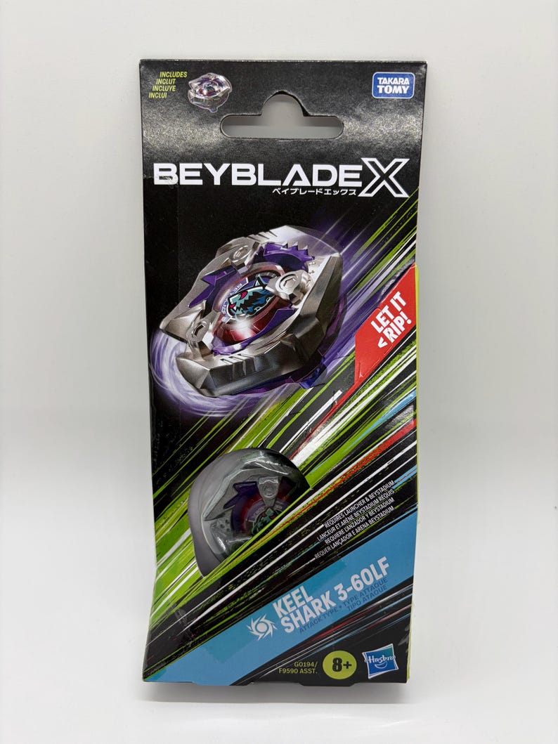 K&ouml;nnte beinhalten: Eine verpackte Beyblade X Spielzeug-Set. Die Verpackung ist schwarz mit dem Beyblade X Logo und japanischem Text. Das Spielzeug ist durch ein transparentes Fenster sichtbar. Der Text "Keel Shark 3-60LF" ist auf der Verpackung aufgedruckt, zusammen mit "Let it Rip!"