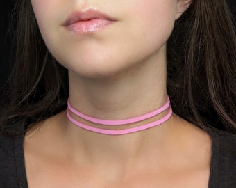 May include: A pink leather choker necklace with two layers.