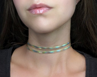May include: A double-layered iridescent choker necklace. The necklace is made of a thin, flexible material and has a subtle shimmer.