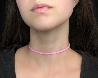 May include: A thin pink leather choker necklace.