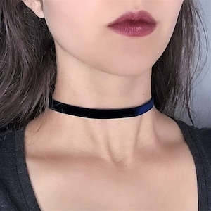 May include: A black velvet choker necklace. The choker is a thin band of velvet fabric that sits close to the neck.