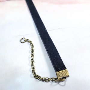 Puede incluir: Un collar gargantilla de terciopelo negro con una cadena y cierre de color dorado. La gargantilla es un dise&ntilde;o sencillo y elegante, perfecto para a&ntilde;adir un toque de sofisticaci&oacute;n a cualquier atuendo.