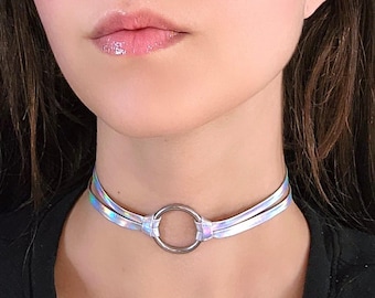 May include: A silver iridescent choker necklace with a large silver ring in the center.