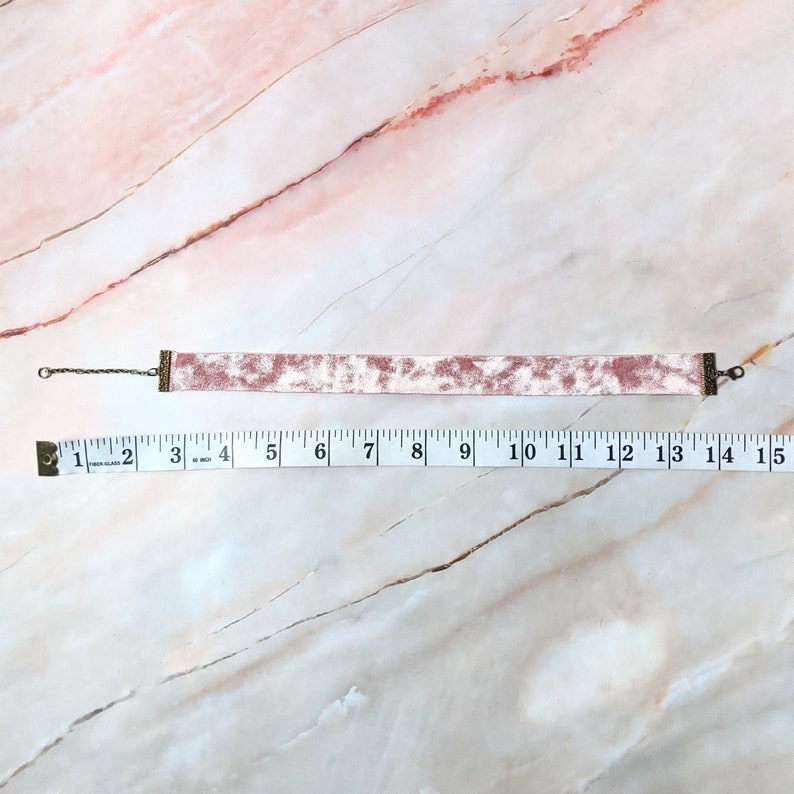 Op de afbeelding: Een roze fluwelen choker met een zilveren ketting en metalen sluitingen. De choker is 35,5 cm lang.