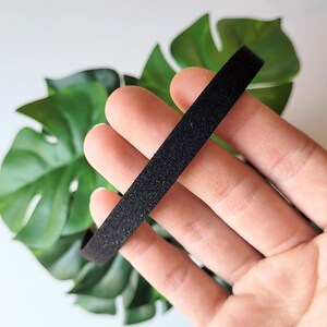 May include: A black velvet ribbon, approximately 1 inch wide, is held in a hand. The ribbon is soft and has a subtle texture.