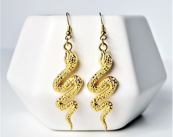 May include: Gold snake dangle earrings. The snake is curled in a S shape with a textured surface.