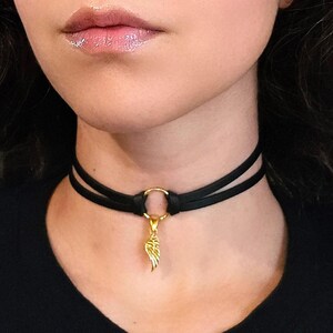 May include: A black leather choker necklace with a gold wing pendant. The choker has a double strap design and a circular clasp.