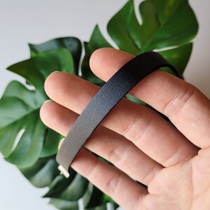 May include: A black leather choker necklace with a smooth, textured finish.