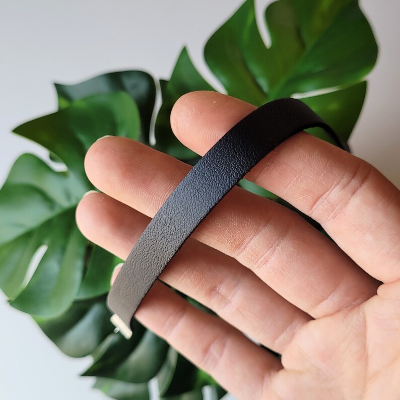 May include: A black leather choker necklace with a smooth, textured finish.