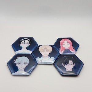 Op de afbeelding: Vijf zeshoekige buttons met speld en anime-stijl karakterillustraties tegen een donkerblauwe achtergrond. Elke button toont een ander individu met verschillende haarkleuren, waaronder zwart, blond, roze en zilver, gerangschikt in een groep.