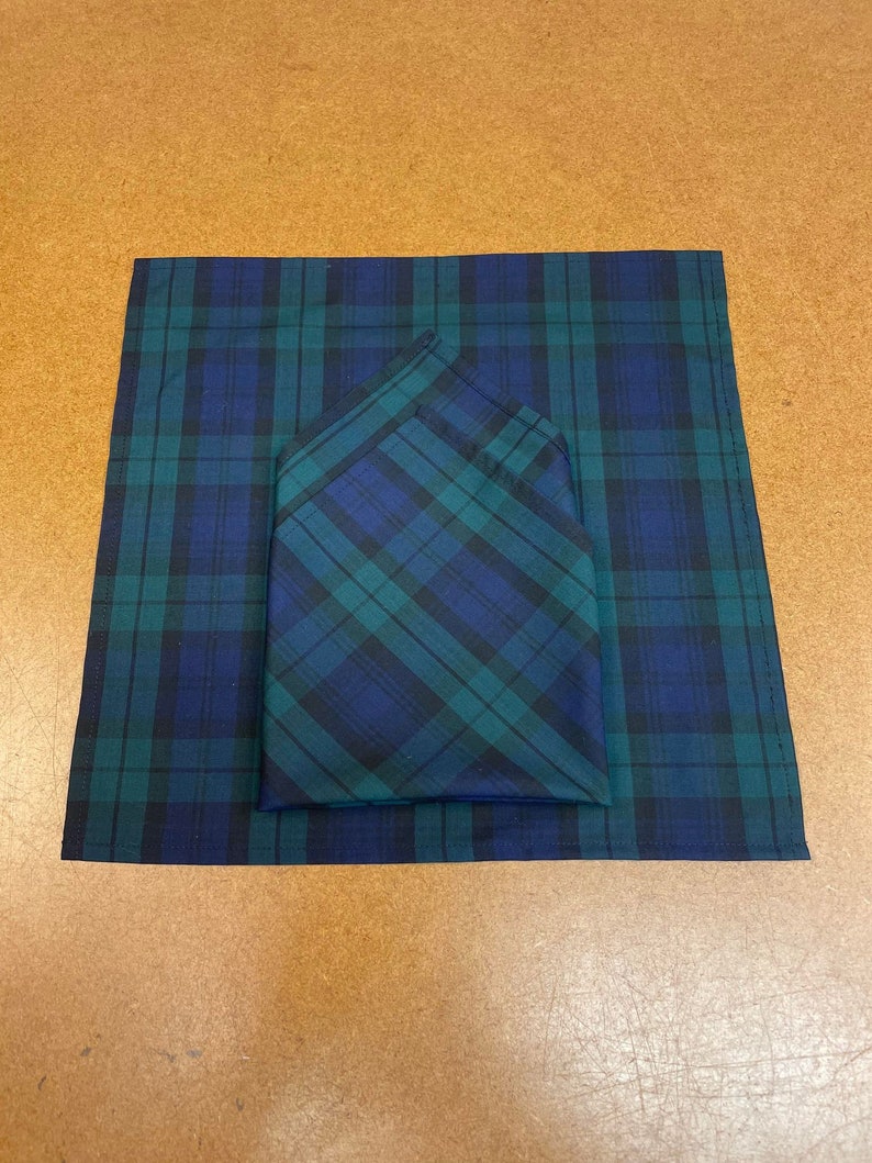 May include: Two blue and green plaid handkerchiefs, one folded on top of the other.