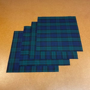 May include: Four plaid fabric handkerchiefs in shades of green and blue, stacked on top of each other.
