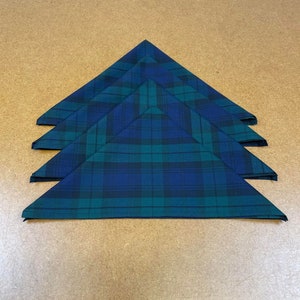 May include: Four folded green and blue plaid fabric napkins.