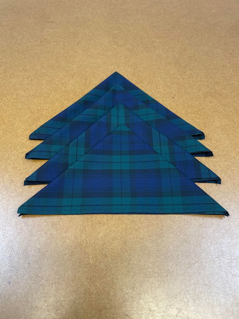 May include: Four folded green and blue plaid fabric napkins.
