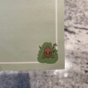 May include: A cartoon illustration of a brown creature with a surprised expression peeking out from behind green foliage.