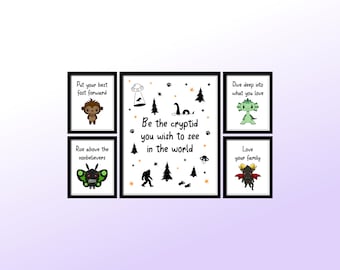 Op de afbeelding: Set van zes zwart ingelijste prints met witte achtergronden en kleurrijke illustraties van mythische wezens. De prints bevatten inspirerende citaten zoals "Zet je beste voet vooruit" en "Wees het cryptide dat je in de wereld wilt zien".