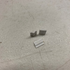 May include: Three white plastic pieces, two are rectangular and one is a curved shape.