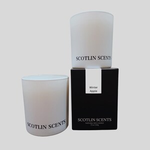 May include: Two white frosted glass candle jars with black labels that read "Scotlin Scents". The smaller jar is on top of a black box with a white label that reads "Winter Apple" and "Scotlin Scents Natural Soy Candle 275 ml / 9.3 oz."