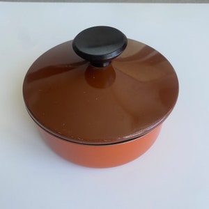 Puede incluir: Una olla de esmalte marrón y naranja con un pomo negro en la tapa.