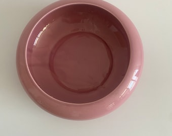 May include: A large, round, pink ceramic bowl. The bowl is smooth and glossy.