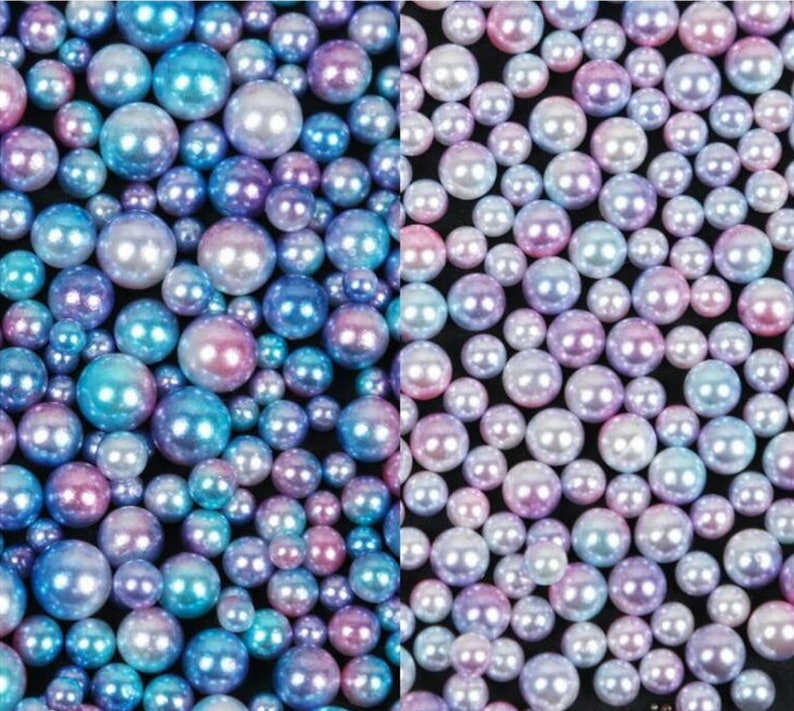 Puede incluir: Un surtido de perlas iridiscentes en varios tama&ntilde;os y colores, incluyendo azul, morado y rosa. Las perlas tienen un acabado brillante y est&aacute;n dispersas sobre una superficie oscura, creando un efecto brillante. Ideal para la creaci&oacute;n de joyas o proyectos de artesan&iacute;a.